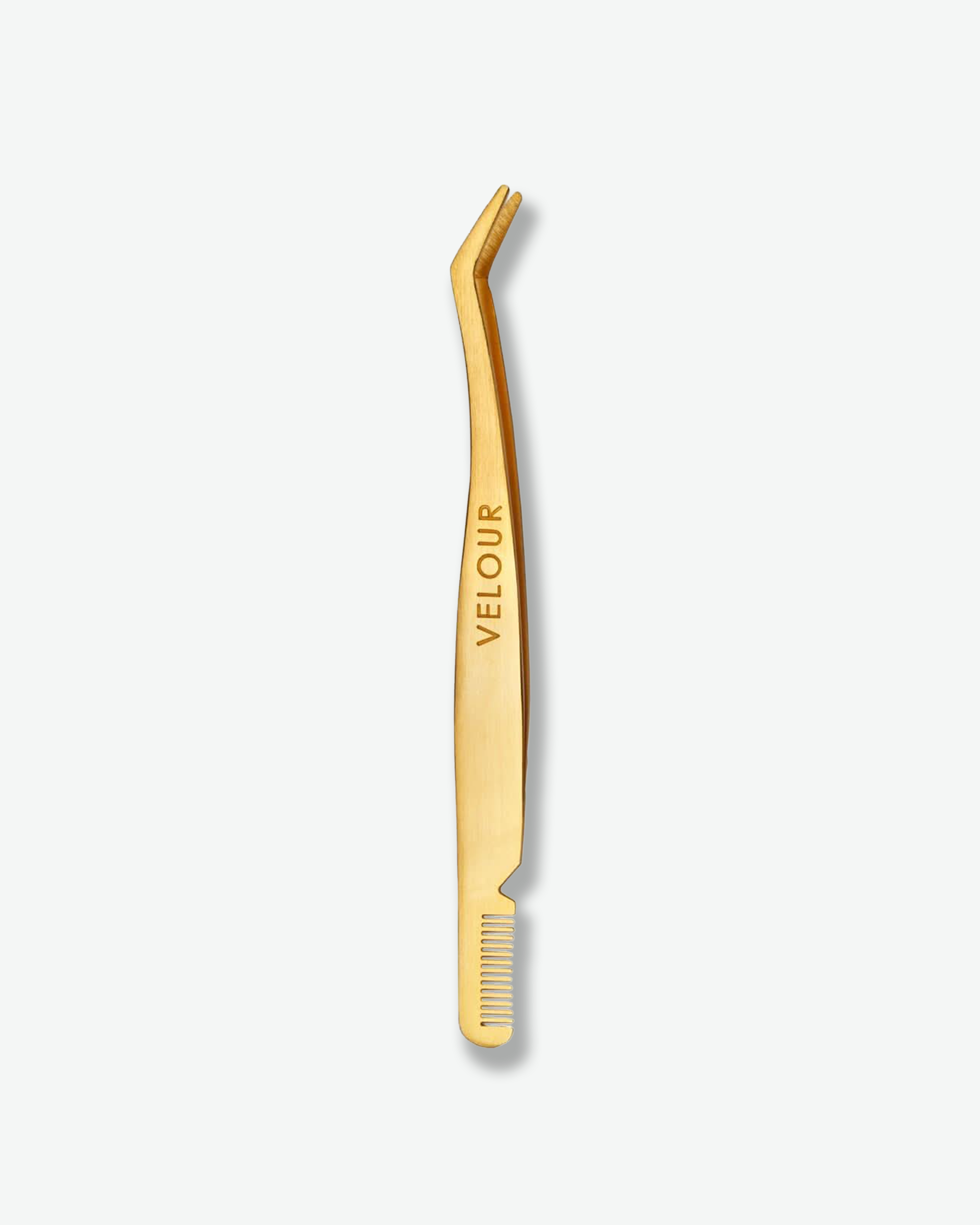 Front view of a Velour gold lash tool featuring an integrated comb against a plain gray background. The sleek beauty tool is crafted with a brushed gold metallic finish, featuring a curved applicator tip at the top and a fine-toothed lash comb built directly into the base of the handle.