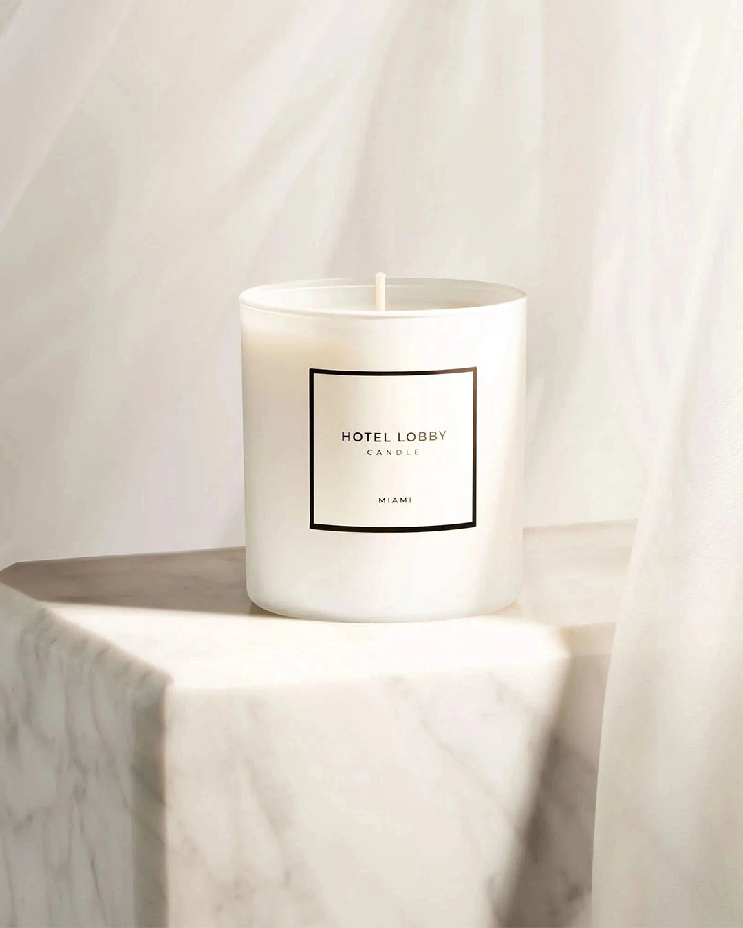 White candle with a label on a marble surface