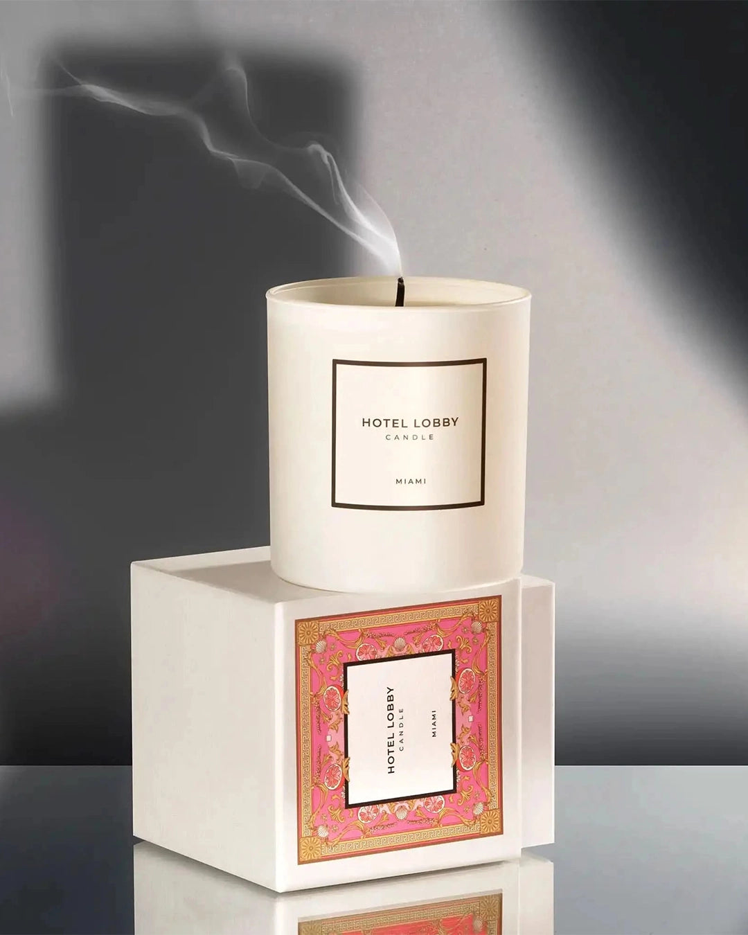 Candle with 'Hotel Lobby' packaging on a reflective surface