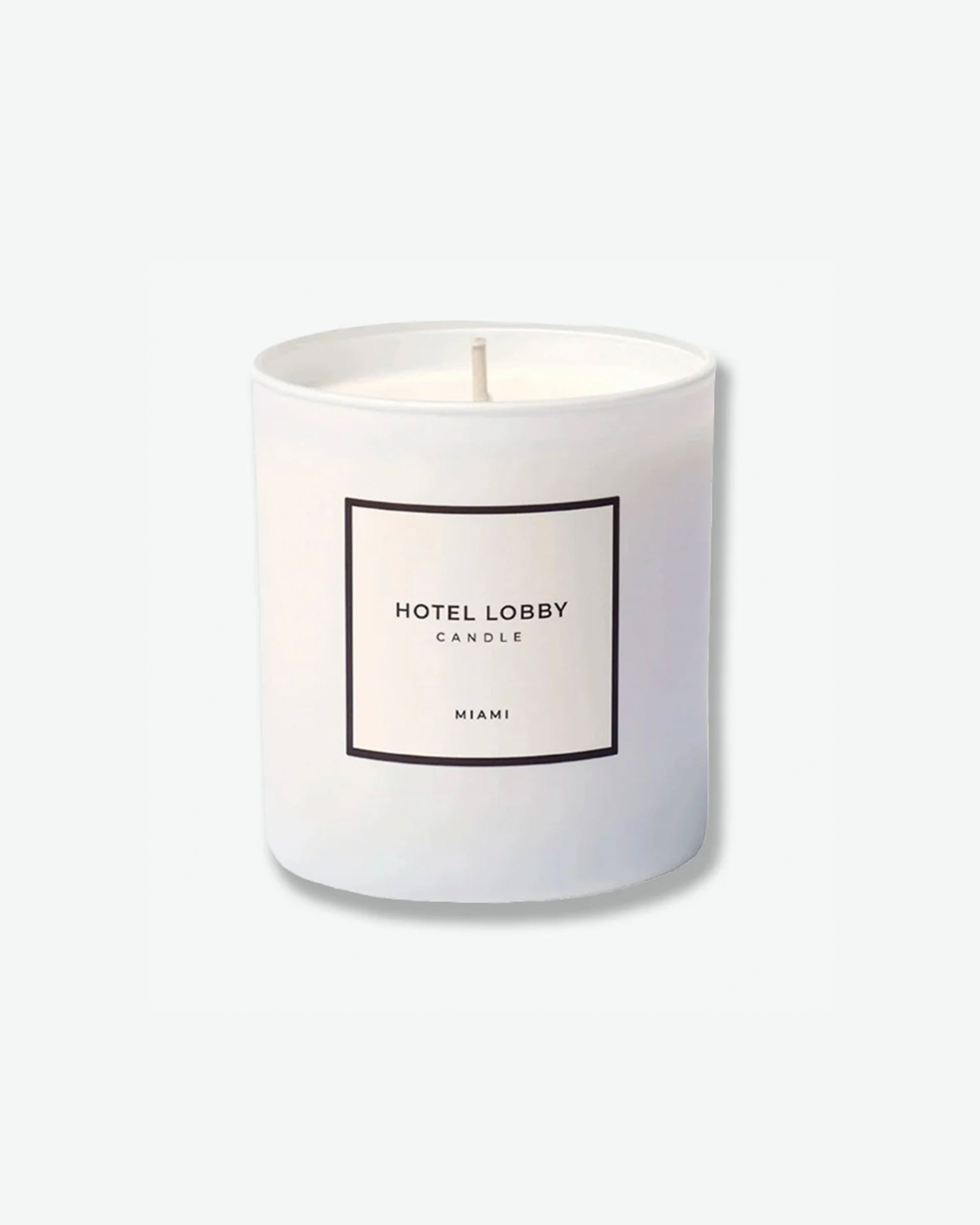 Hotel Lobby Candle Miami scented candle in a matte white glass tumbler with a square white label, isolated against a light grey background.