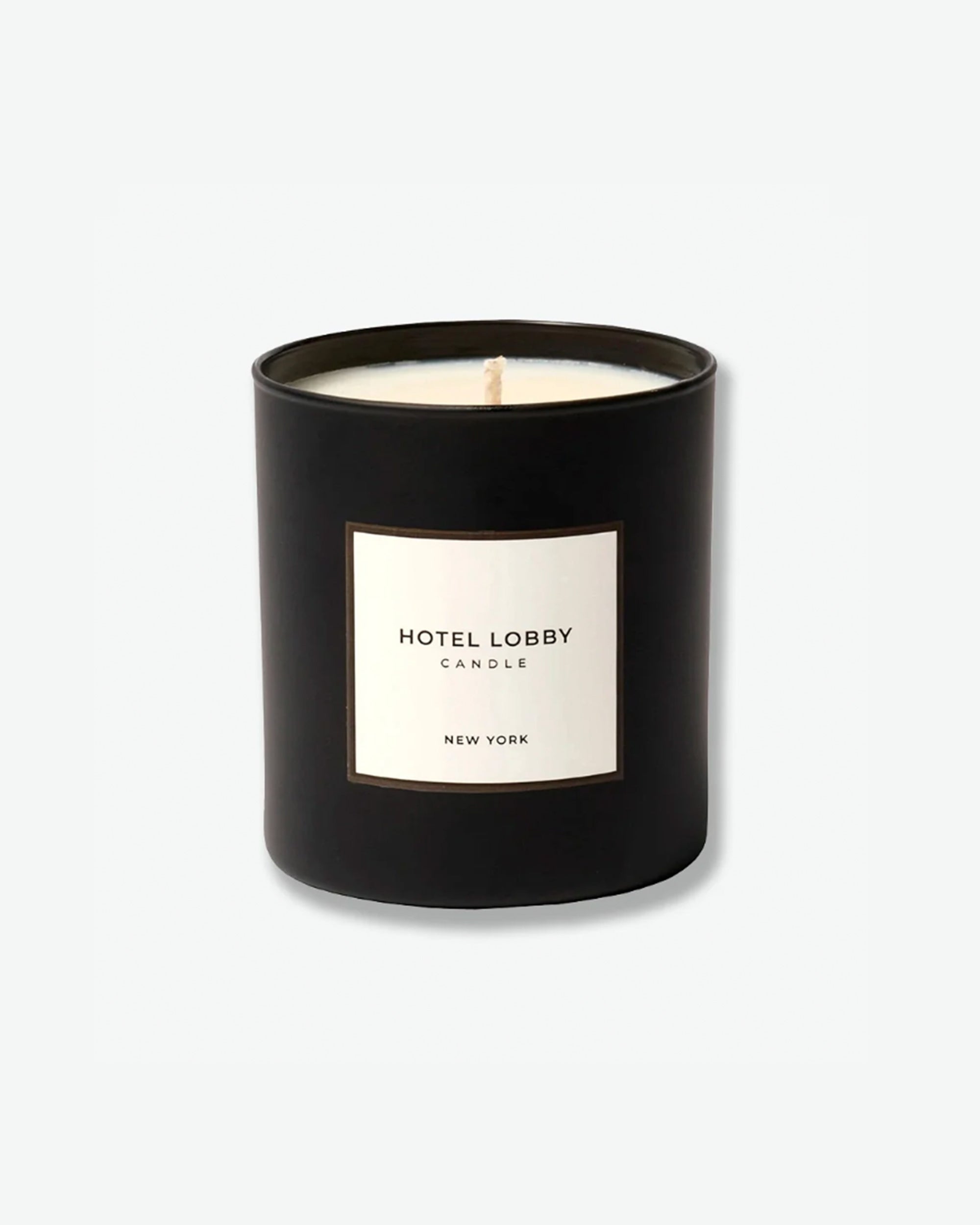 Hotel Lobby Candle New York scented candle in a matte black glass tumbler with a square white label, isolated against a light grey background.