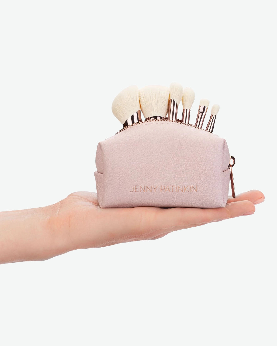 Pink makeup brush set in a case held in a hand on a white background