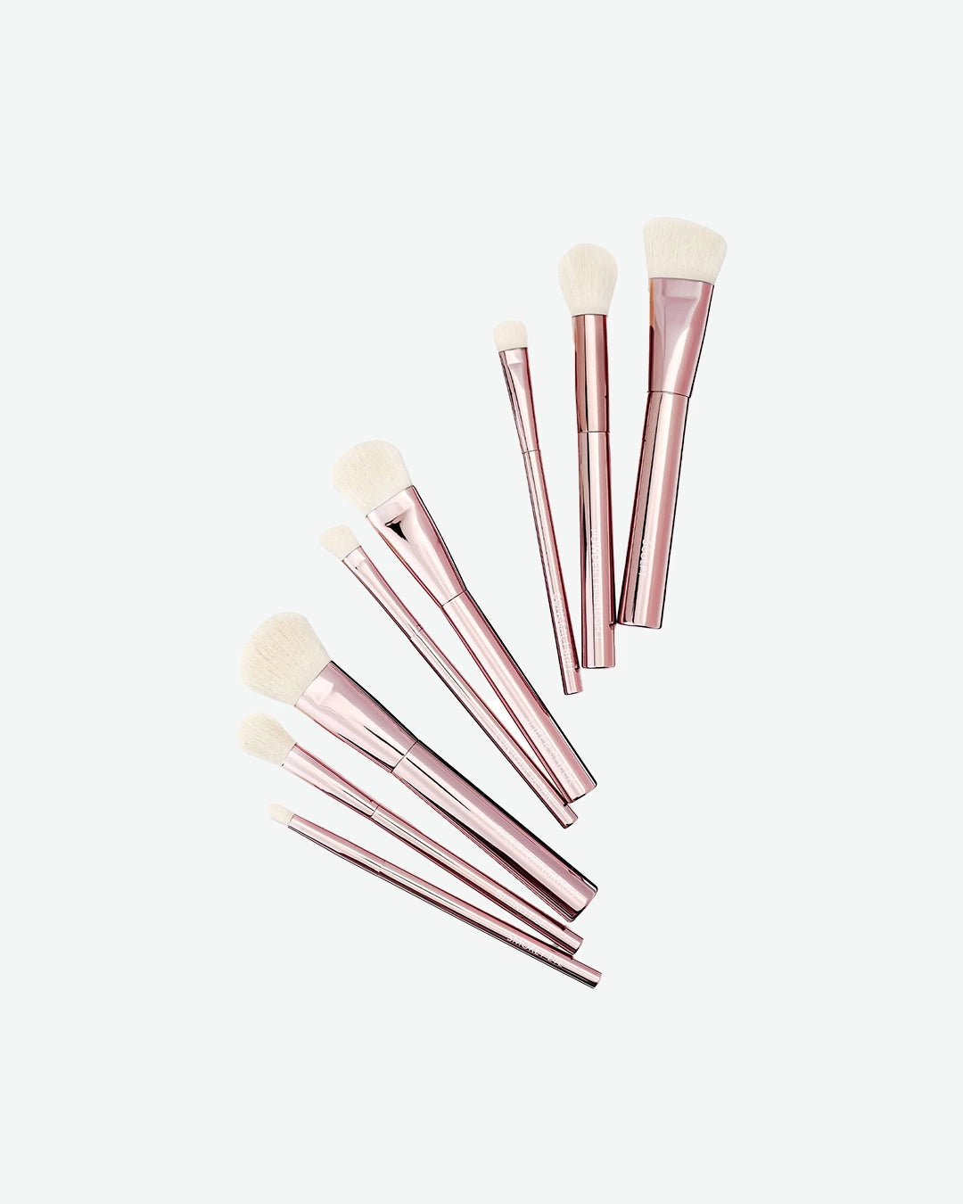 Set of rose gold makeup brushes on a white background