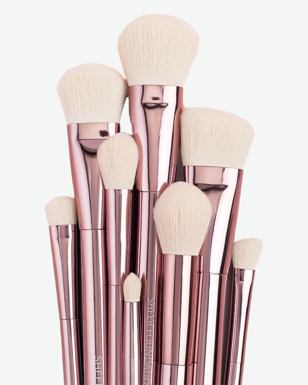 Set of makeup brushes with rose gold handles on a white background