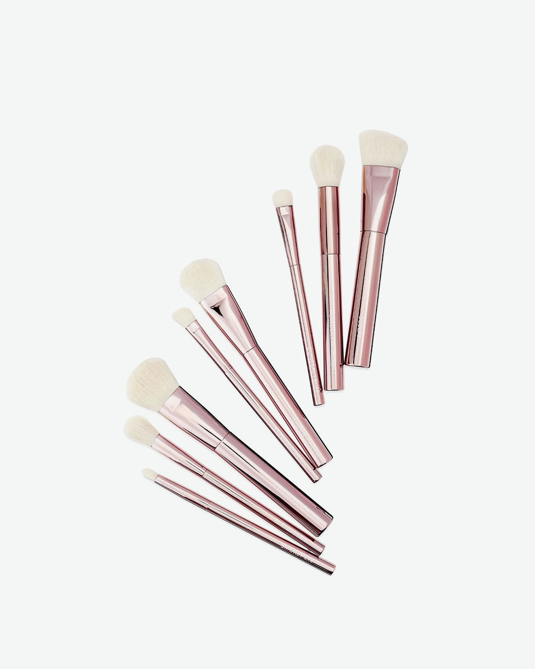 Set of rose gold makeup brushes on a white background