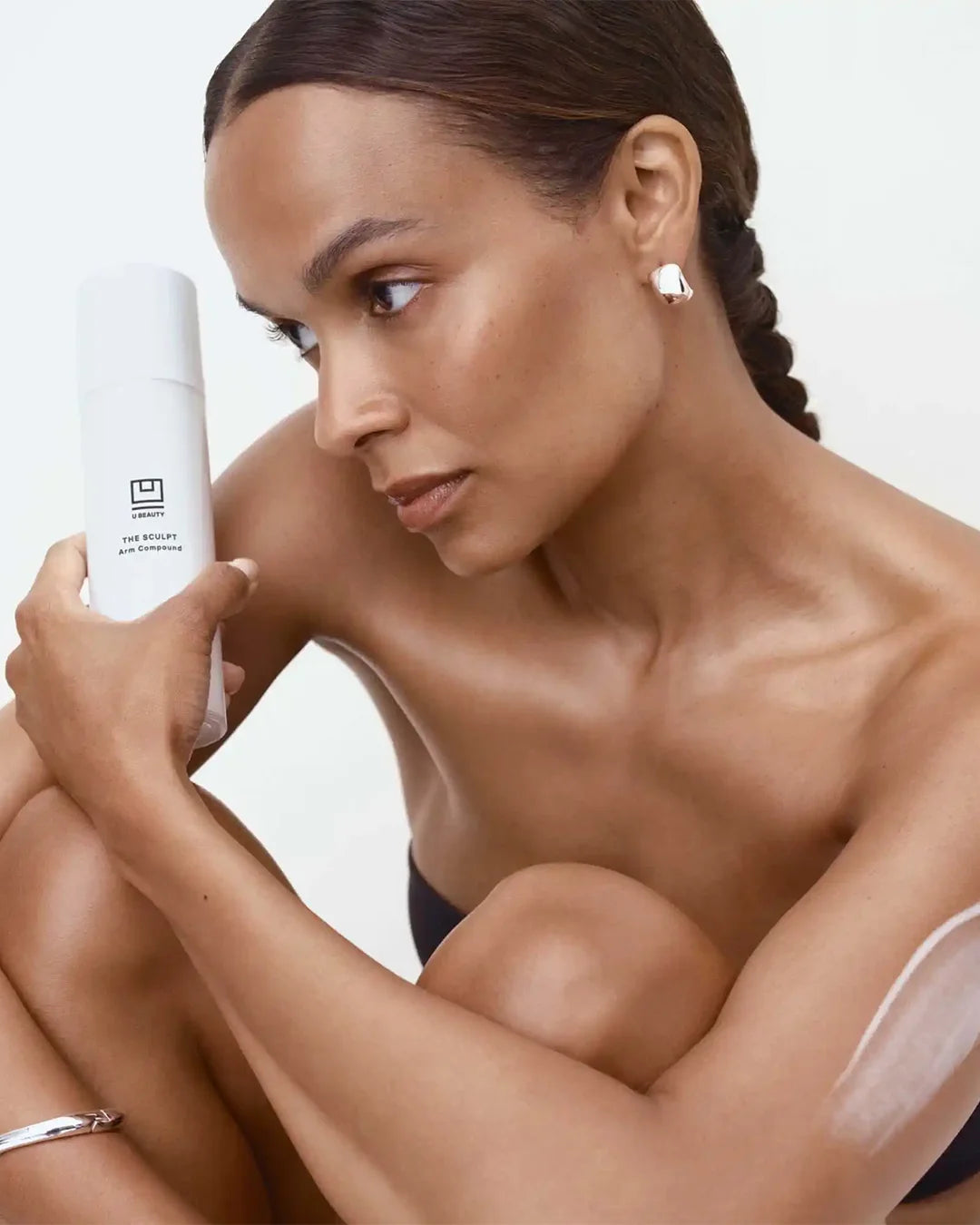 Woman holding a skincare product with a neutral background