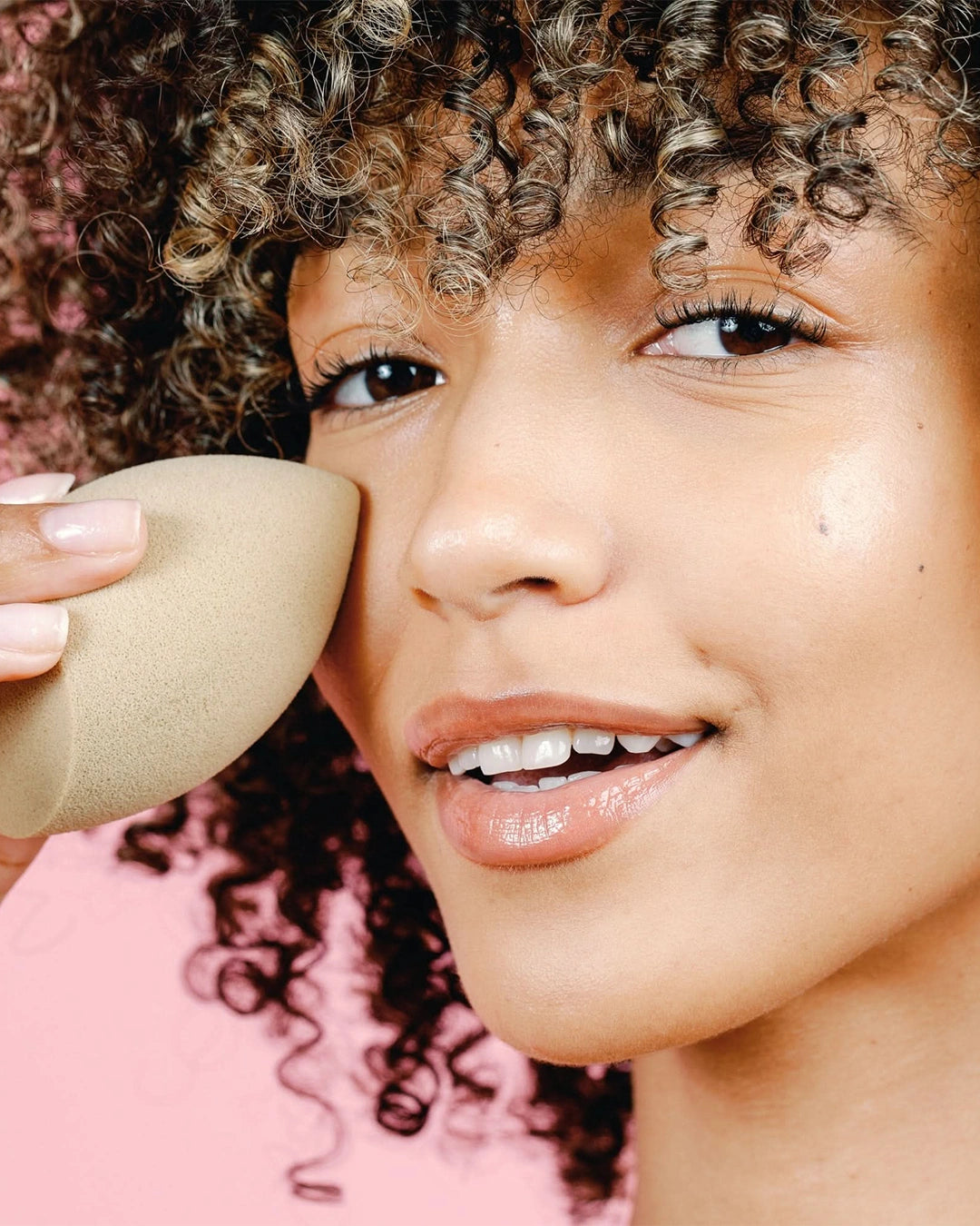 Person using a makeup sponge on their face with a blurred background
