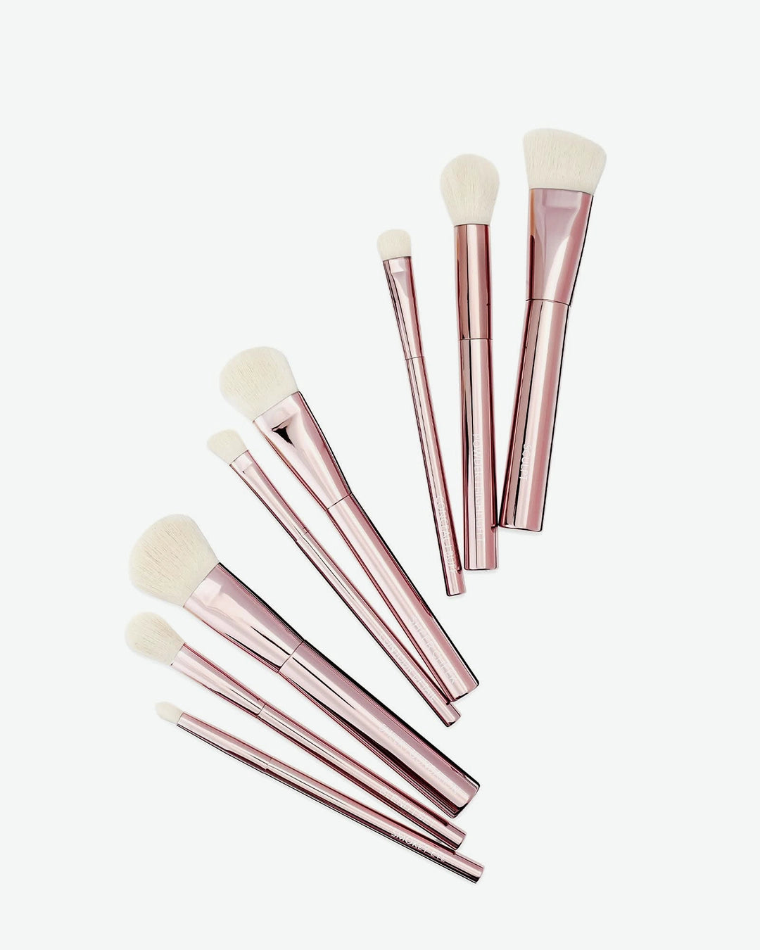 Set of rose gold makeup brushes on a white background