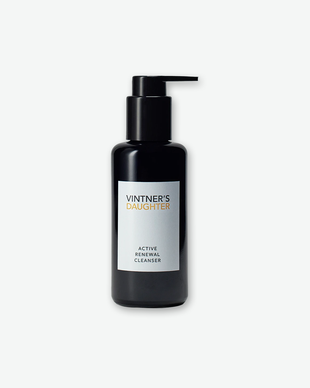 A product shot of a Vintner's Daughter Active Treatment Essence bottle, centered against a plain light gray background. The cylindrical container is crafted from dark violet-black glass and is fitted with a black spray pump mechanism. It features a vertical white rectangular label on the front that displays the brand name "VINTNER'S DAUGHTER" along with the product title "ACTIVE TREATMENT ESSENCE".