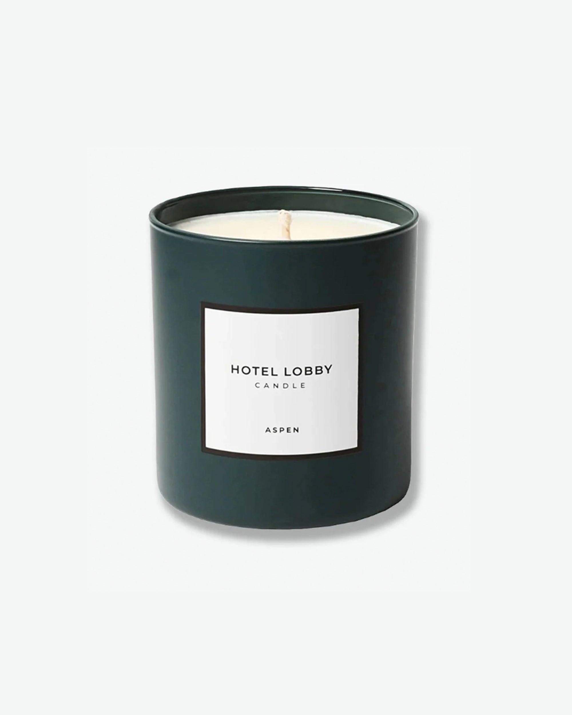 Hotel Lobby Candle Aspen scented candle in a matte forest green glass tumbler with a square white label, isolated against a light grey background.