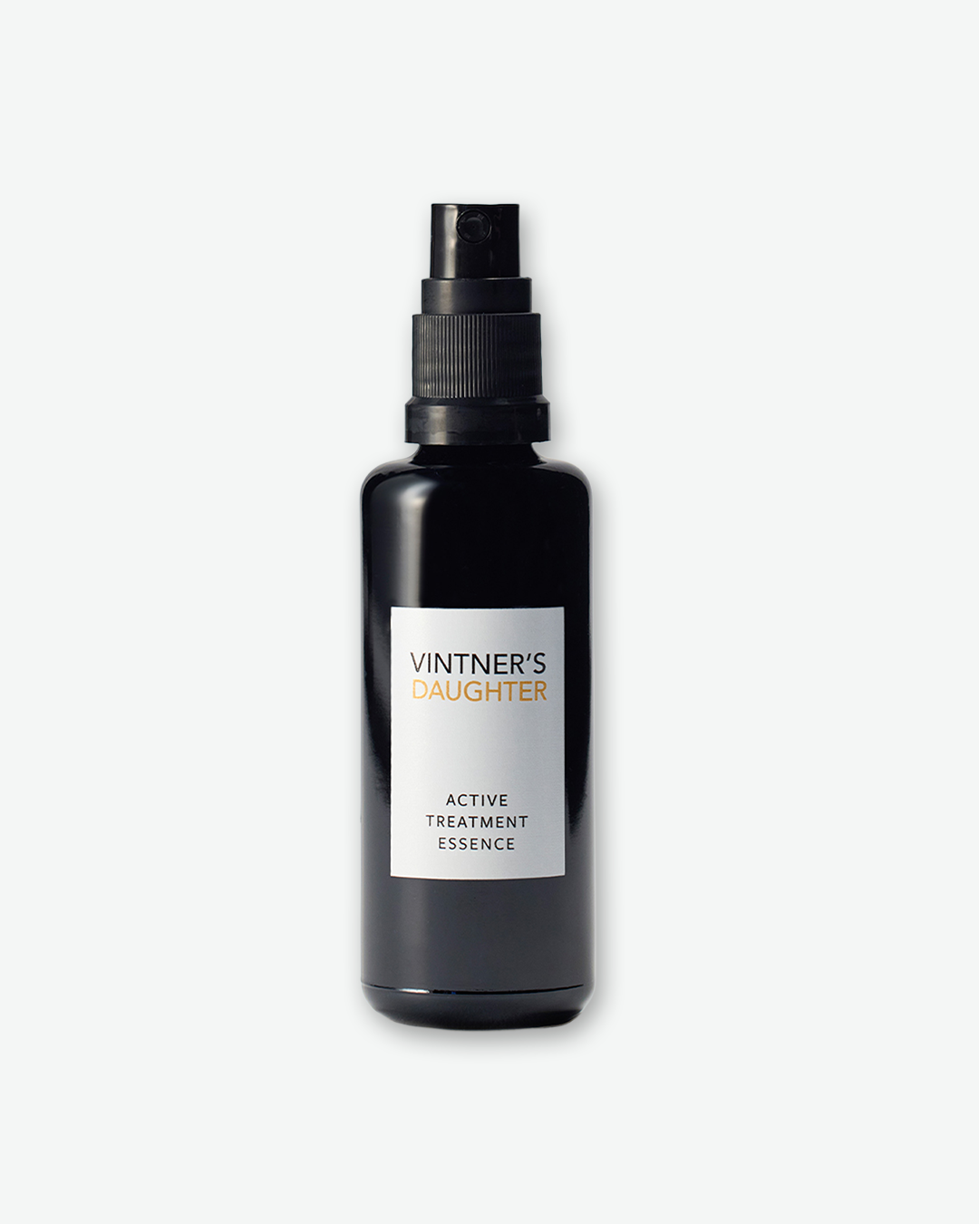 Vintner's Daughter Active Treatment Essence in a dark black glass bottle with a black spray pump nozzle and a vertical white label, isolated against a light grey background.