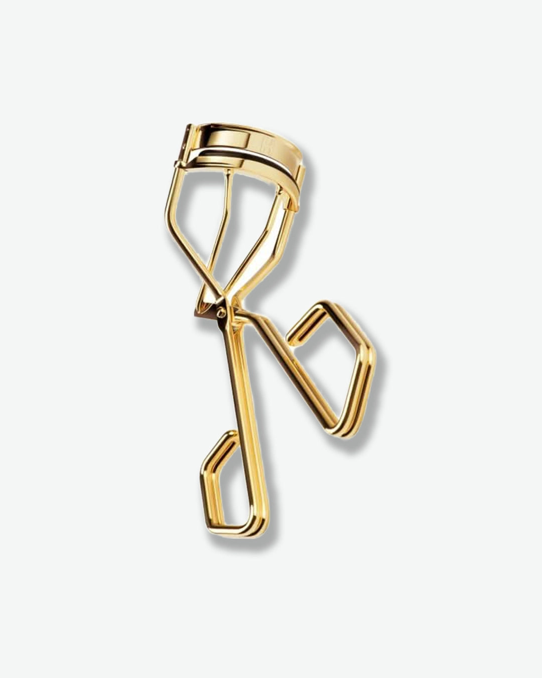 Gold eyelash curler on a white background