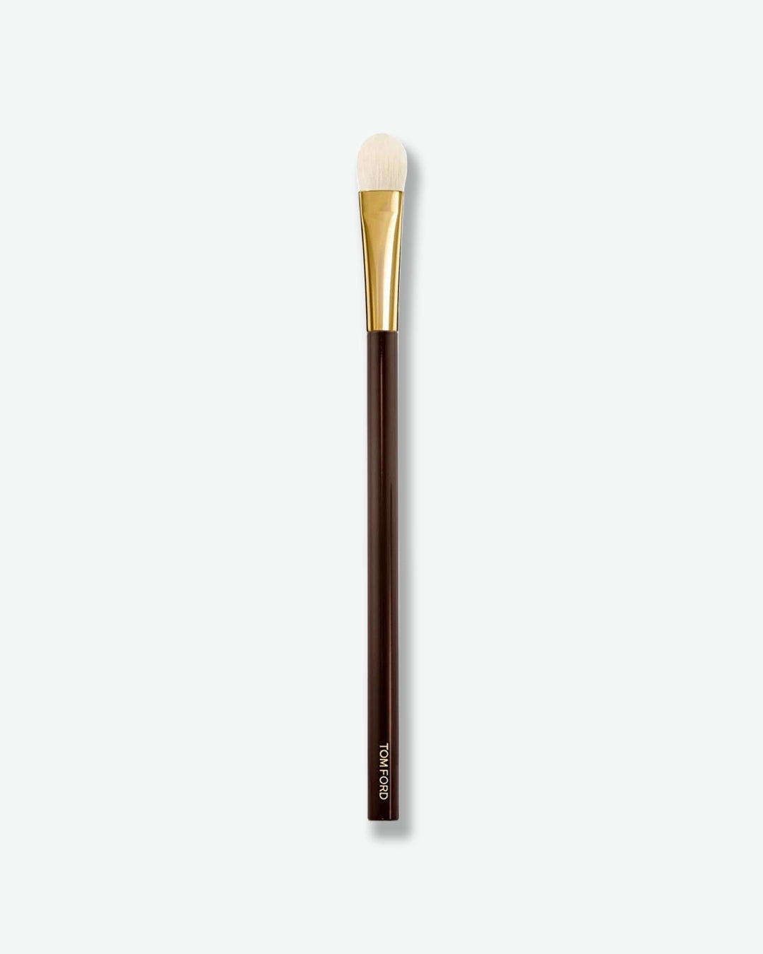 A slim makeup brush with a rounded, flat-topped white bristle head, a shiny gold ferrule, and a dark brown handle. Designed for precise eyeshadow application, blending, or concealer placement, the brush is displayed vertically against a light gray background.