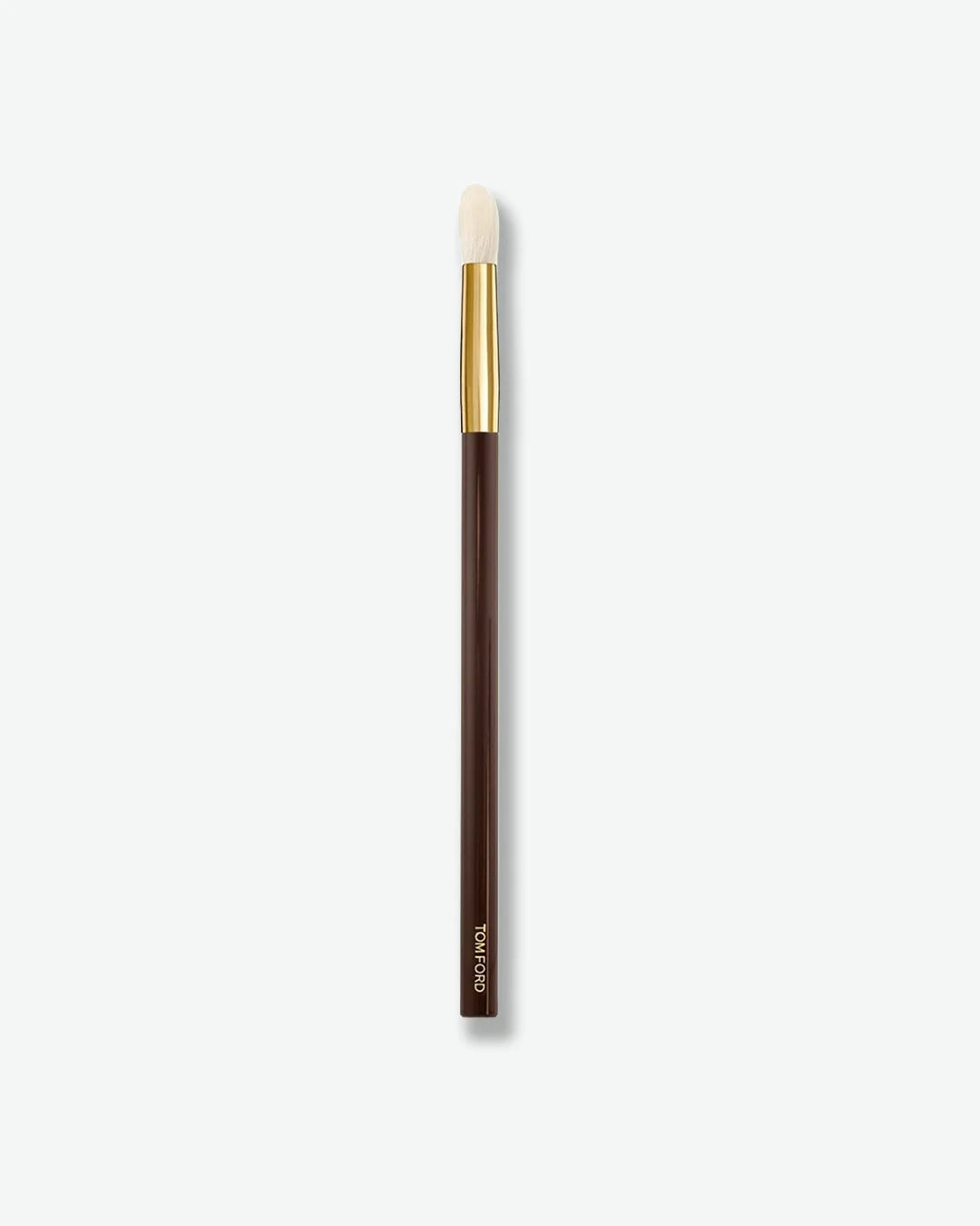 A slim makeup brush with a tapered, rounded white bristle head, a shiny gold ferrule, and a dark brown handle. Designed for precise eyeshadow application and blending, the brush is displayed vertically against a light gray background.