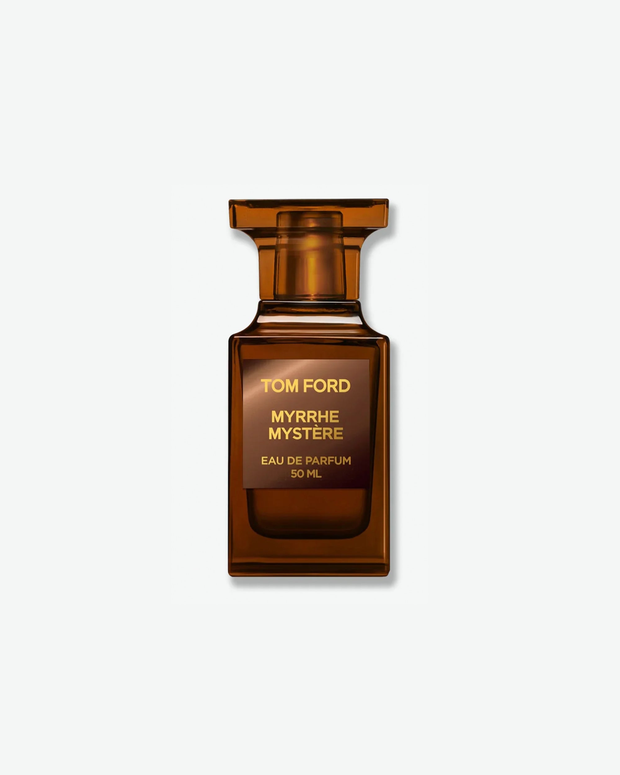 Product shot of Tom Ford Myrrhe Mystère Eau de Parfum. The fragrance is presented in a 50ml architectural, translucent amber-brown glass bottle reminiscent of a chess piece. It features a square metallic bronze-brown label with the brand name and fragrance details printed in a warm gold-toned font, casting a soft shadow against a clean, minimal light grey background.