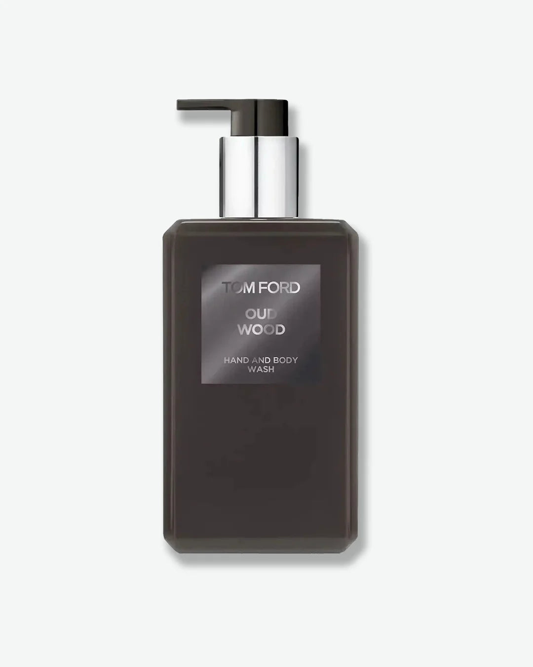 A rectangular dark brown pump bottle labeled “Tom Ford Oud Wood Hand and Body Wash.” The bottle features a sleek, minimalist design with a silver collar and dark pump dispenser. Displayed against a light gray background.