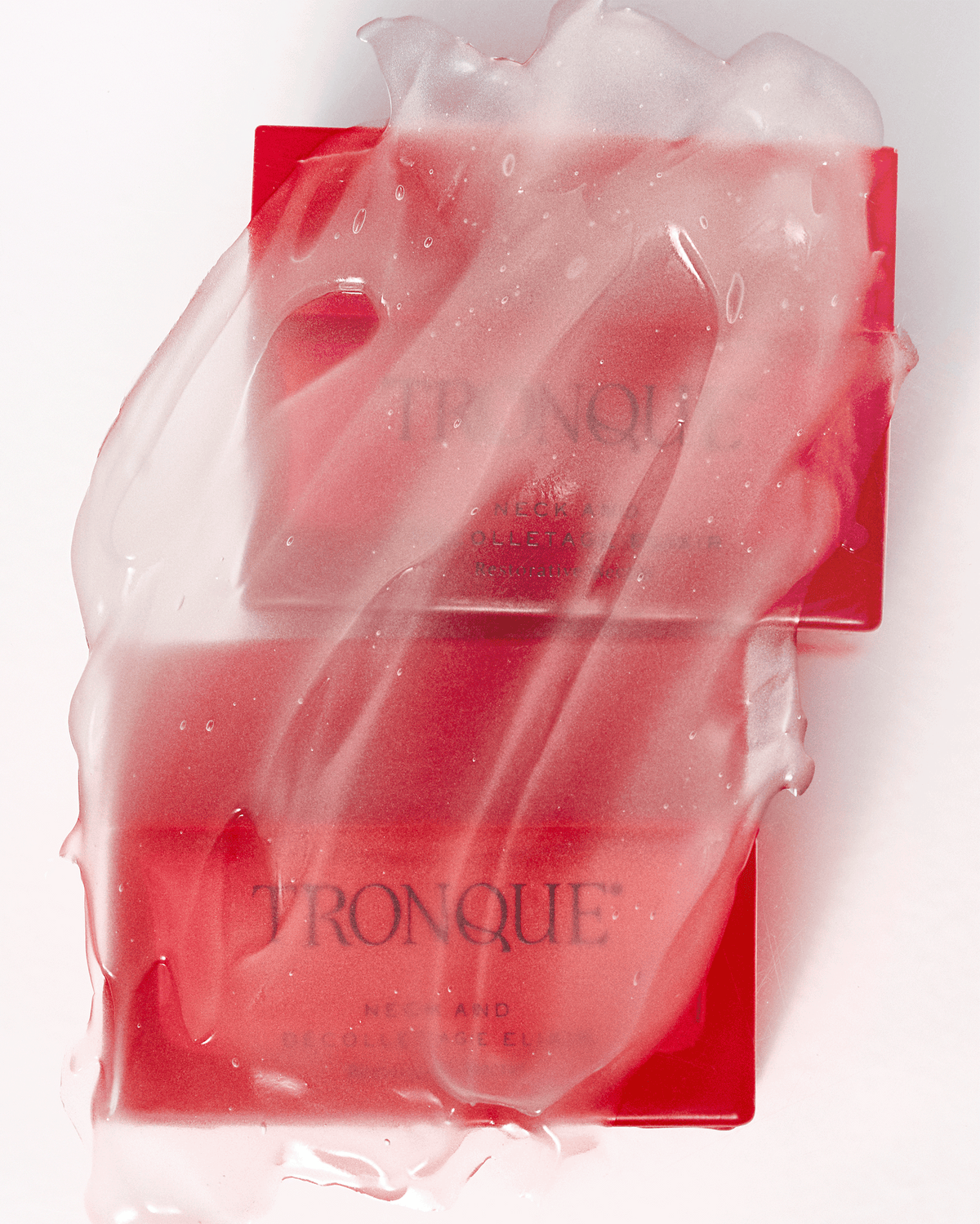 Artistic close-up of two red Tronque Neck and Décolletage Elixir jars partially covered in a glossy translucent gel texture.