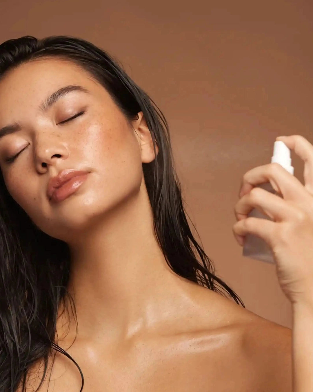Woman applying a product to her face with a brown background