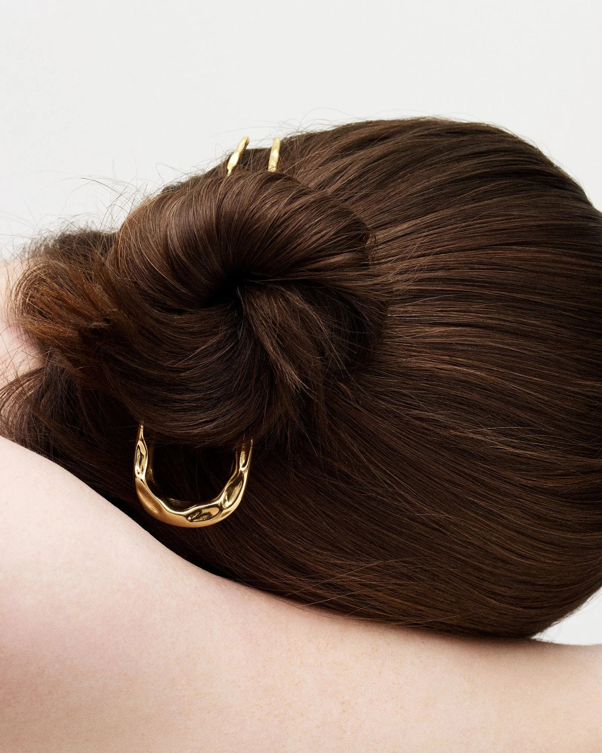 Hair bun with gold hair tie on a plain background