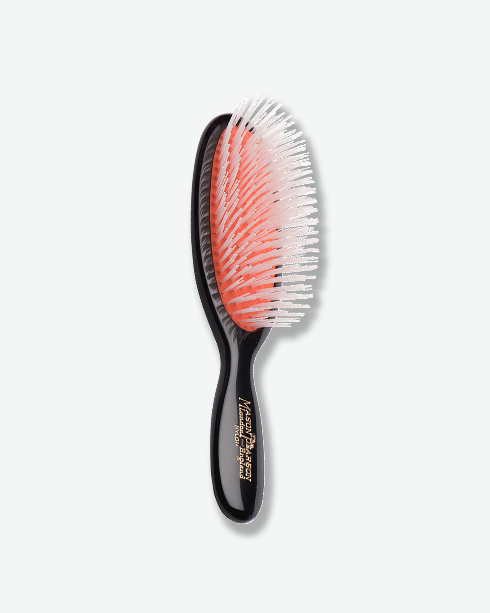 Front view of a Mason Pearson classic dark ruby oval hairbrush featuring a bright orange rubber cushion with a mixture of black nylon and boar bristles, and gold text on the handle reading "The Mason Pearson London - England Nylon & Bristle".