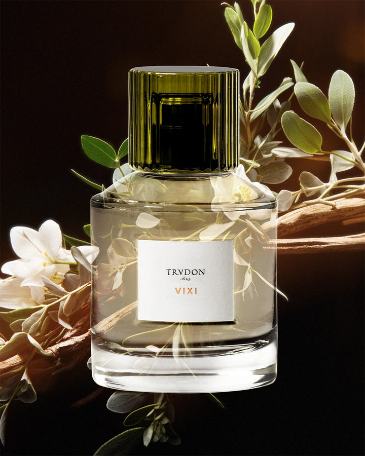 Trudon VIXI perfume bottle with green cap and floral elements on a dark background
