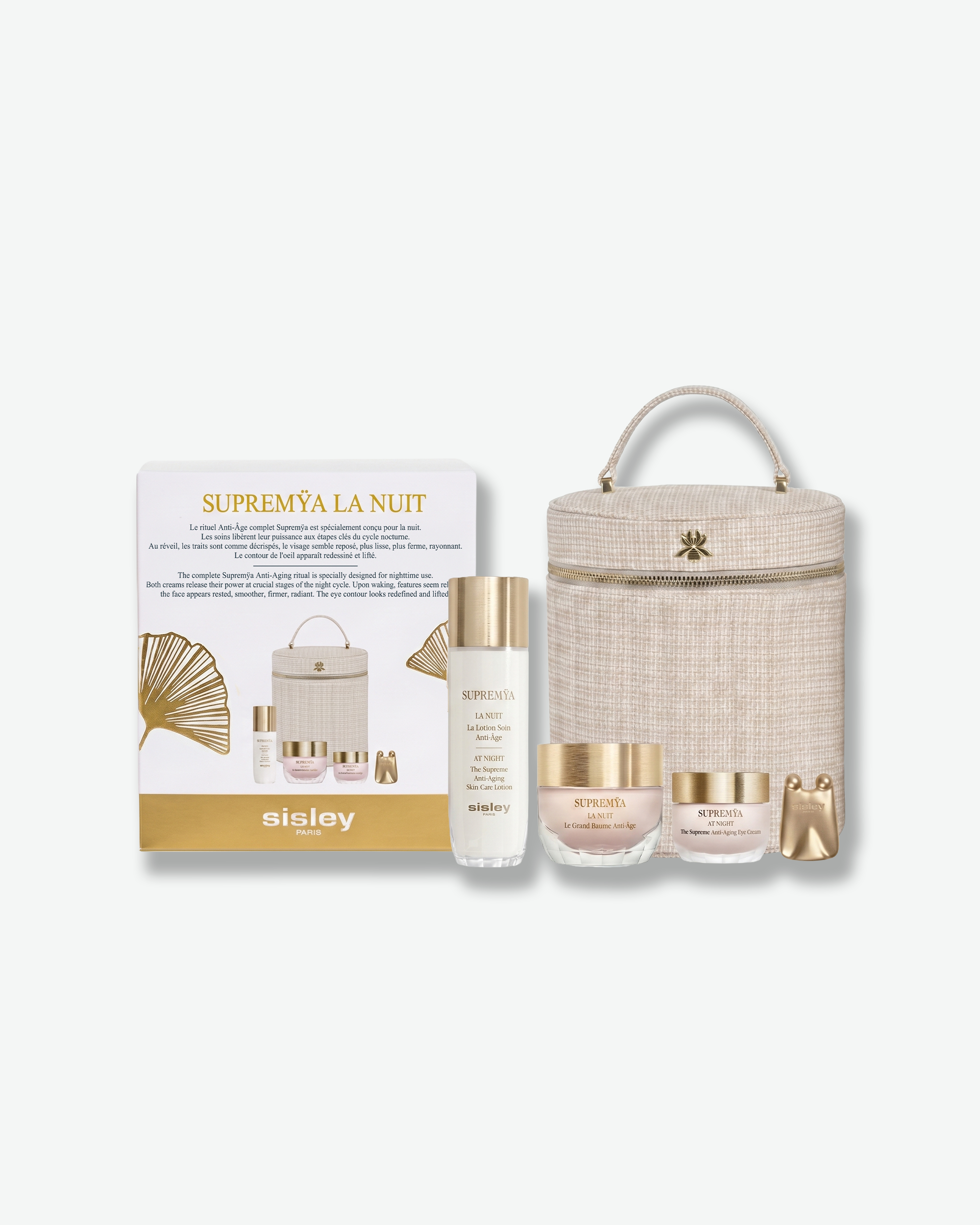 Sisley skincare gift set featuring a white and gold box, a clear bottle with a gold cap, two cream jars with gold lids, and a beige woven cylindrical carrying case with a top handle, all arranged on a light gray background.