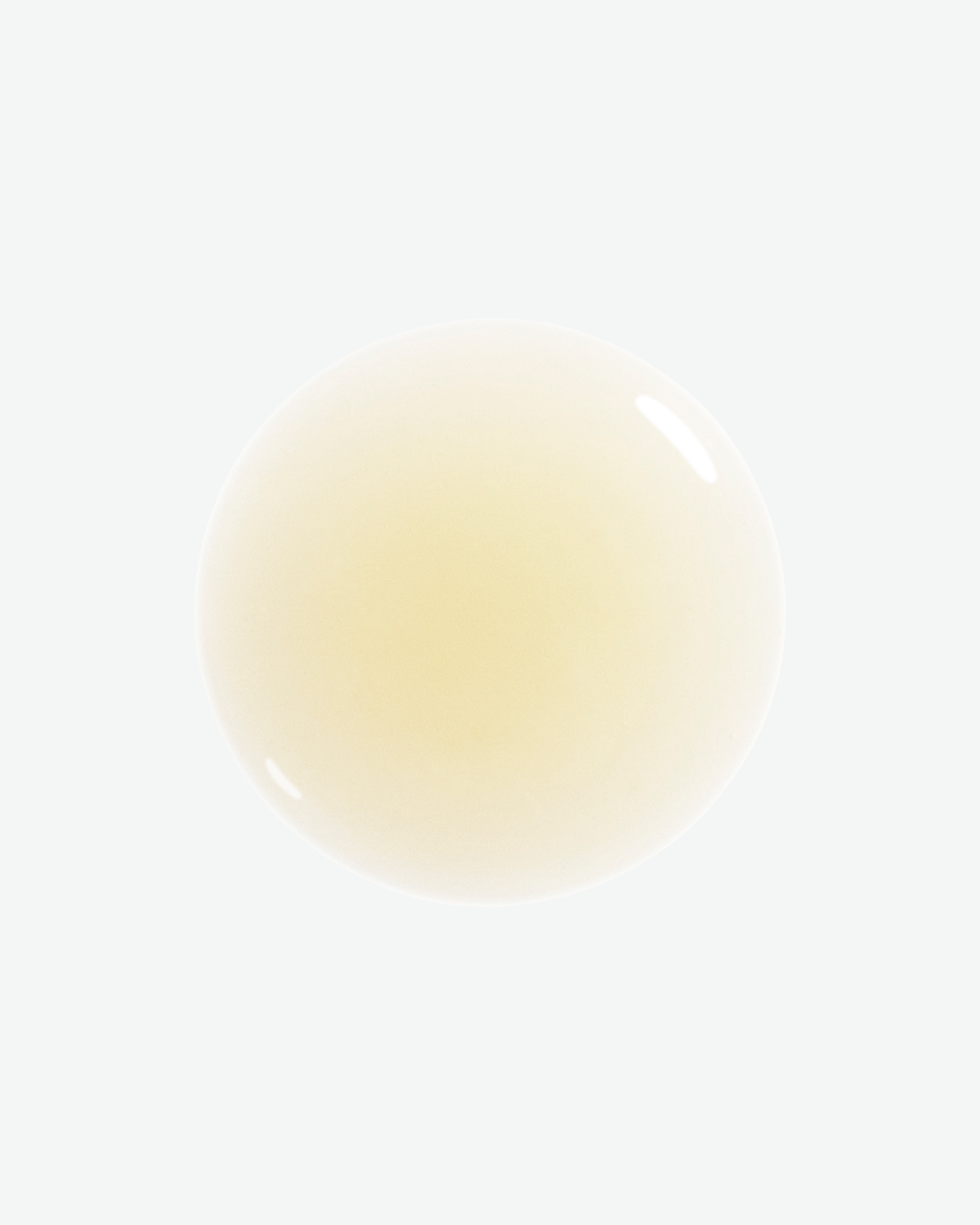A translucent, pale yellow circular drop of liquid with a glossy reflection on a white background.