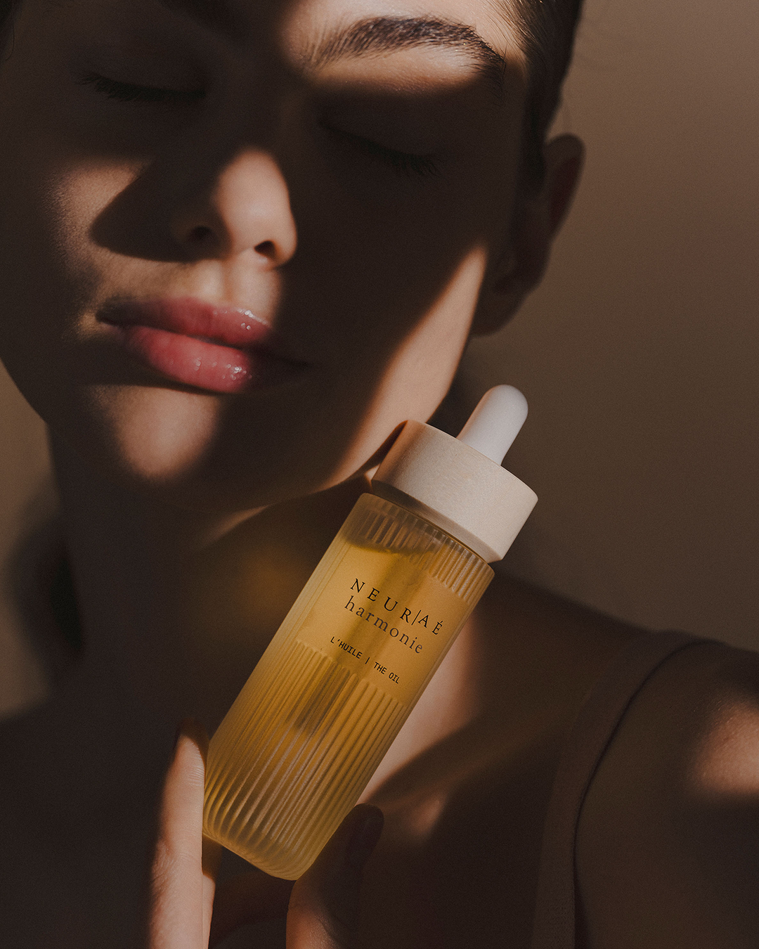 Person holding a bottle of NEURAE harmonie oil with a blurred background