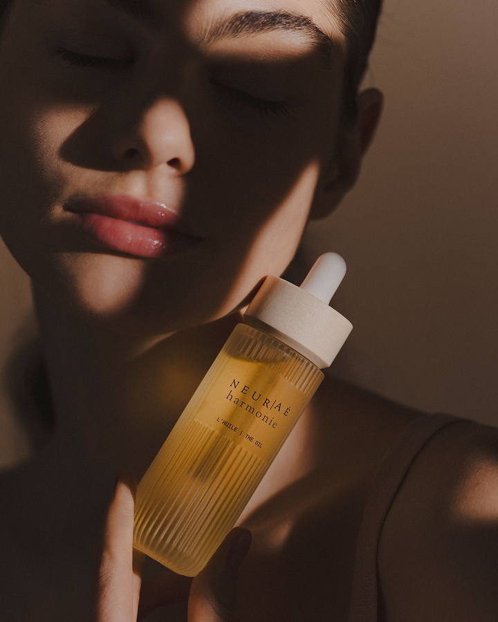 Person holding a bottle of NEURAE harmonie oil with a blurred background