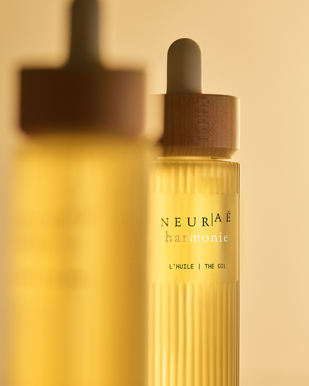 Neuráé harmonie oil bottle with wooden dropper on a beige background