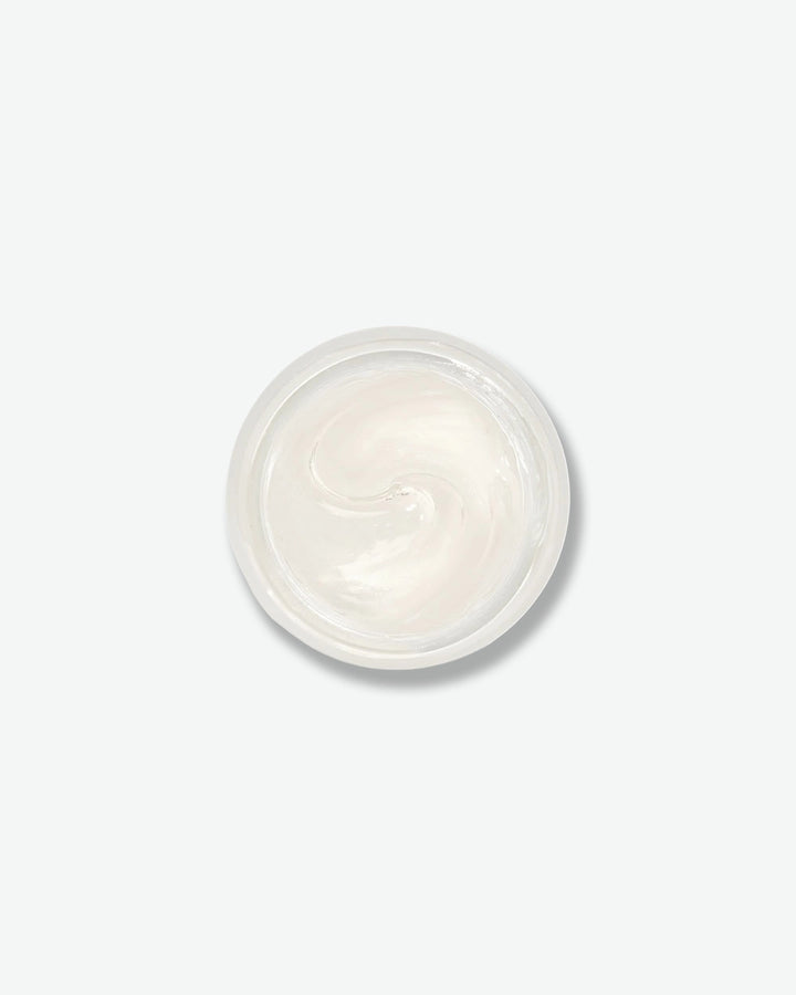 Small round container of white cream on a light gray background