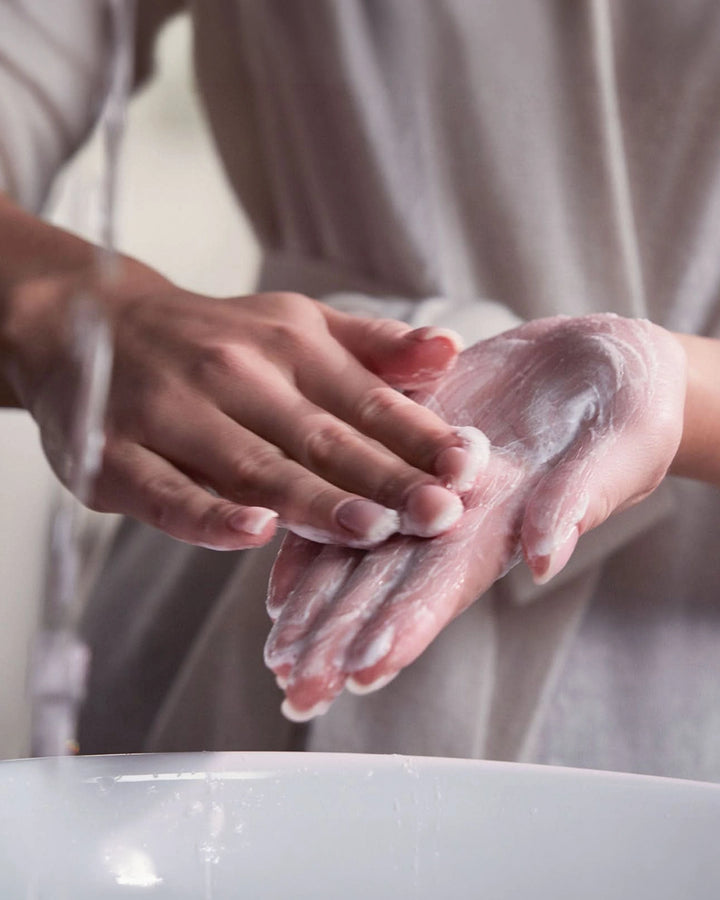 Person with mixing powder on her hand under running water