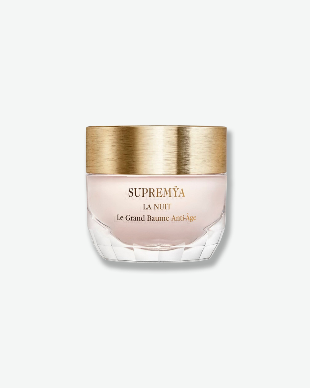 Front view of a Sisley Paris Supremÿa La Nuit "Le Grand Baume Anti-Âge" jar against a plain gray background. The curved, heavy glass jar has a frosted pale pink appearance and features gold branding text, paired with a wide, brushed gold metallic cap.