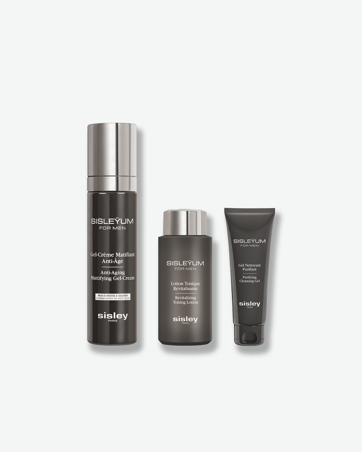 A Sisleyum skincare set for men featuring three matte dark gray and silver containers: a pump bottle, a small lotion bottle, and a squeezable tube against a white background.