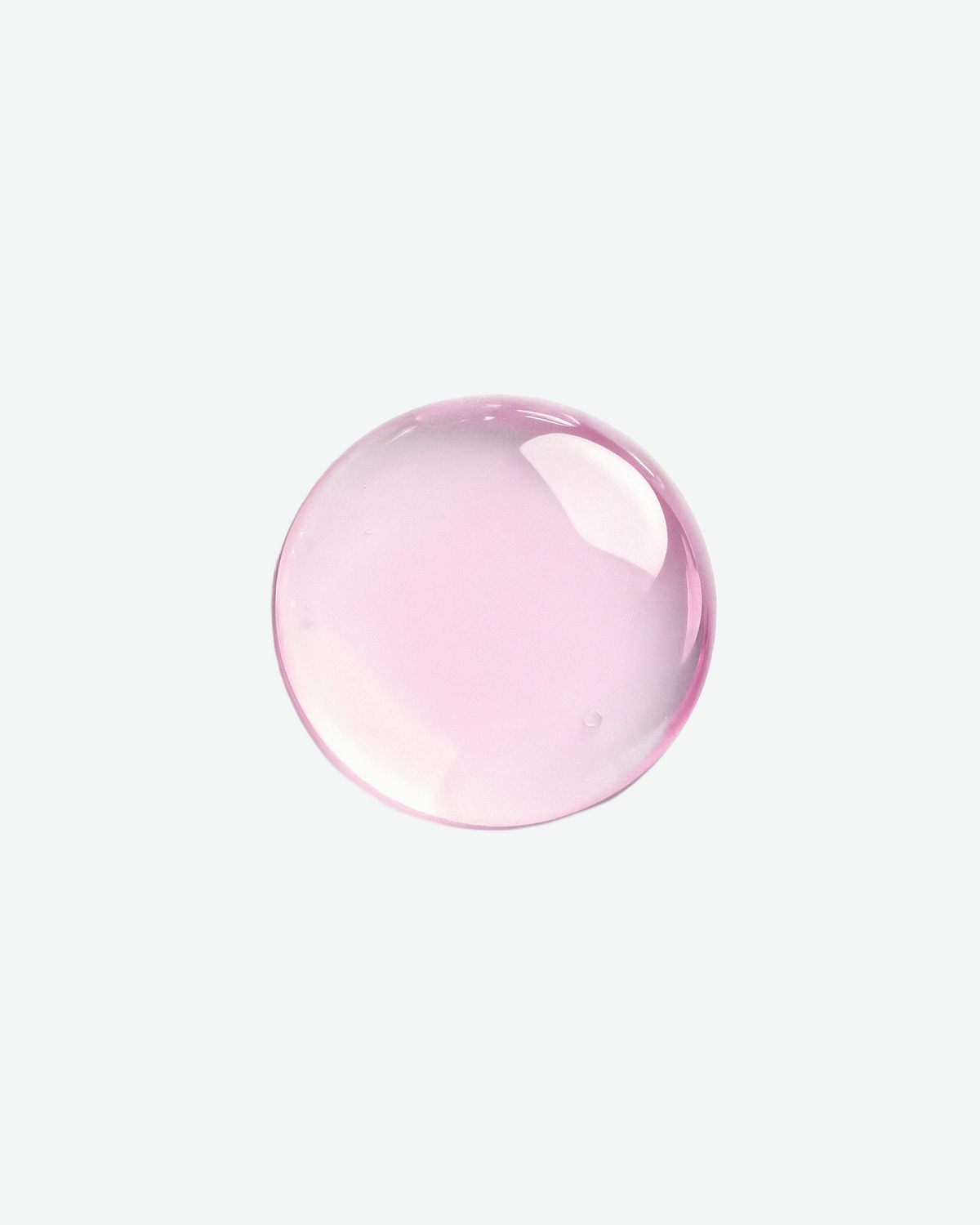 A circular droplet of translucent light pink cosmetic liquid, showing product texture against a plain white background.