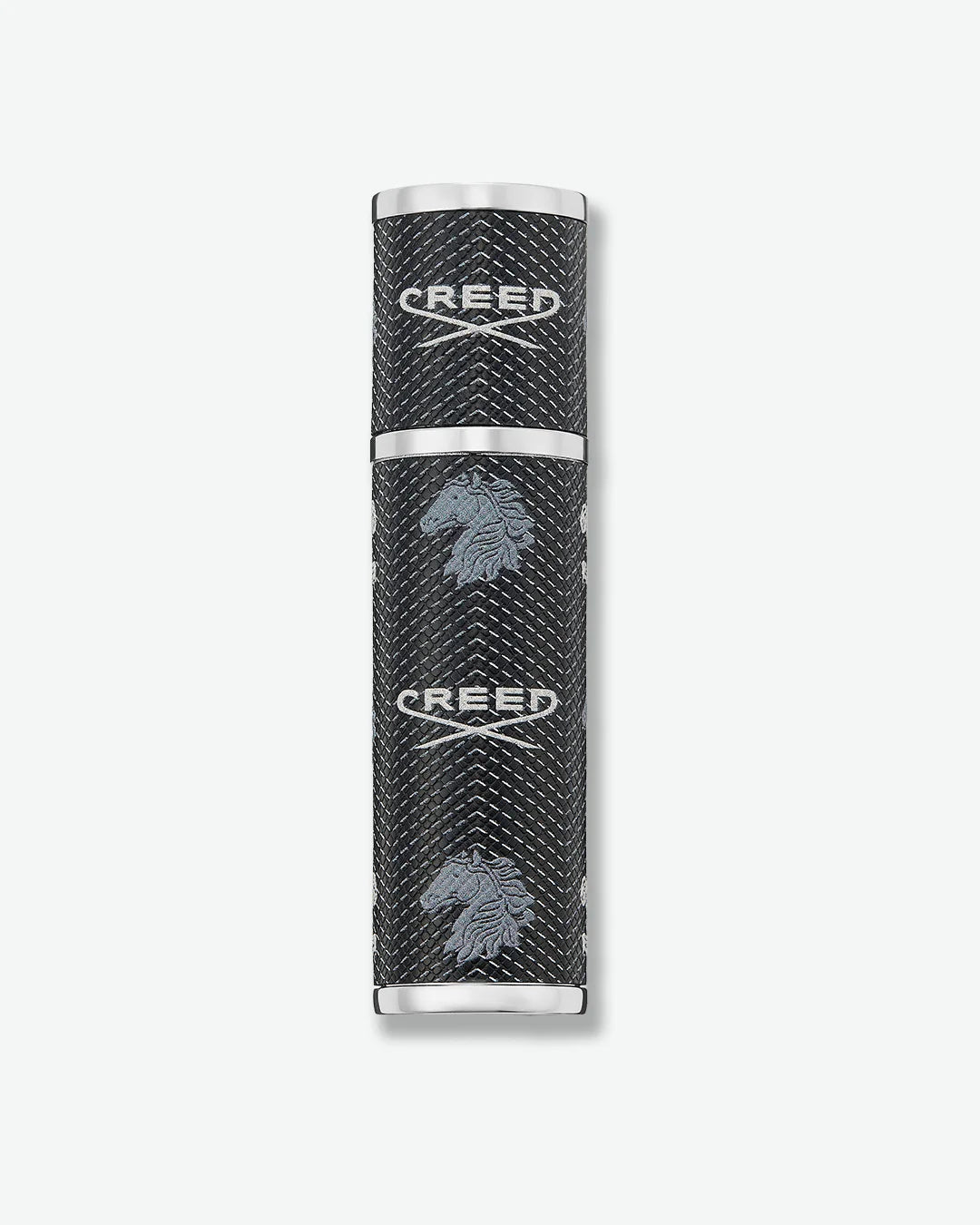 Black cylindrical Creed fragrance travel atomizer with textured leather-like finish, silver-tone metal accents, and repeating Creed logo and horse emblem on a light gray background.
