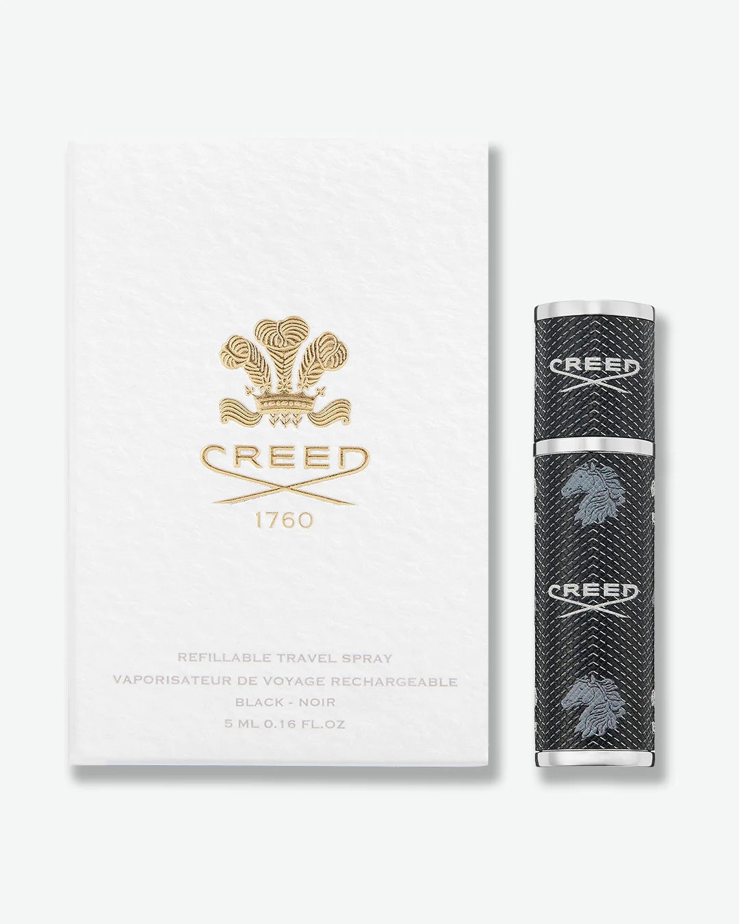 Black cylindrical Creed fragrance travel atomizer with textured leather-like finish, silver-tone metal accents, and repeating Creed logo and horse emblem stood next to a white packaging box with gold Creed logo on a light gray background.