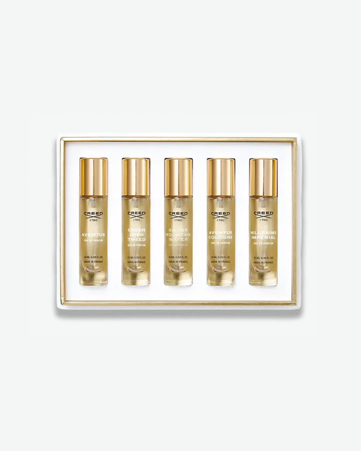 A Creed men's fragrance discovery set displaying five travel spray vials in a white box with a thin gold inner trim, featuring scents like Aventus, Green Irish Tweed, and Silver Mountain Water, isolated on a light grey background.