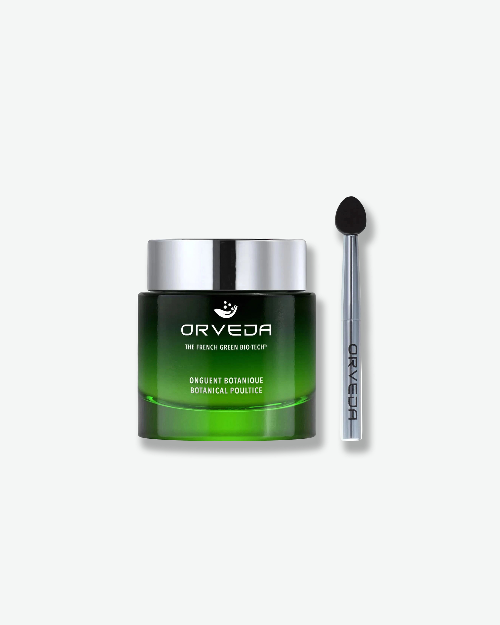 Product shot featuring an Orveda "Onguent Botanique / Botanical Poultice" skincare jar standing next to its applicator tool. The dark-to-bright green gradient glass jar with a silver lid sits beside a slender silver metallic wand tool topped with a black silicone spatula head.
