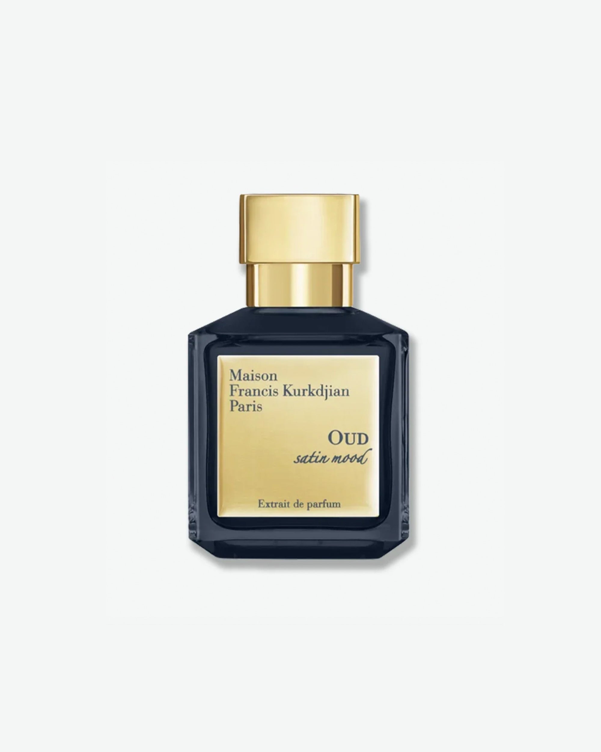 Product shot showing the front of a Maison Francis Kurkdjian Oud Satin Mood Extrait de Parfum bottle. The square, cubic flacon is made of deep, translucent navy blue glass and features a bright metallic gold label on the front with the brand and fragrance details. It is topped with a heavy, polished gold square cap and casts a soft shadow to the right against a minimal white background.