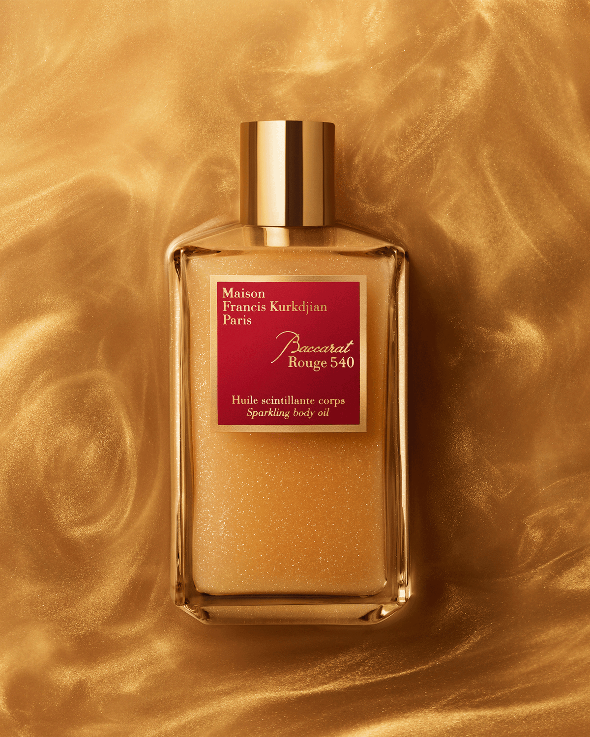 Baccarat Rouge 540 Sparkling Body Oil photographed against a rich, molten-gold backdrop that emphasizes the formula’s radiant, light-catching shimmer.