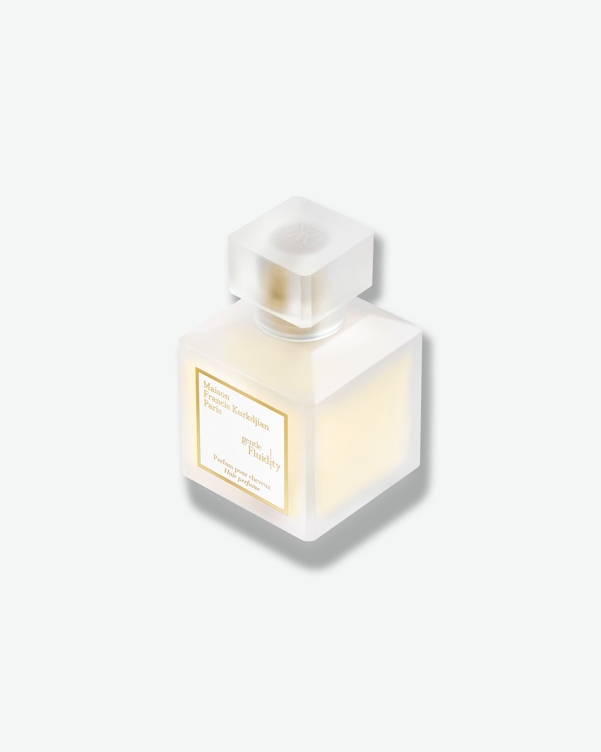 Angled close-up of the Maison Francis Kurkdjian Gentle Fluidity Hair Perfume, highlighting the frosted bottle, translucent cap, and gold detailing.