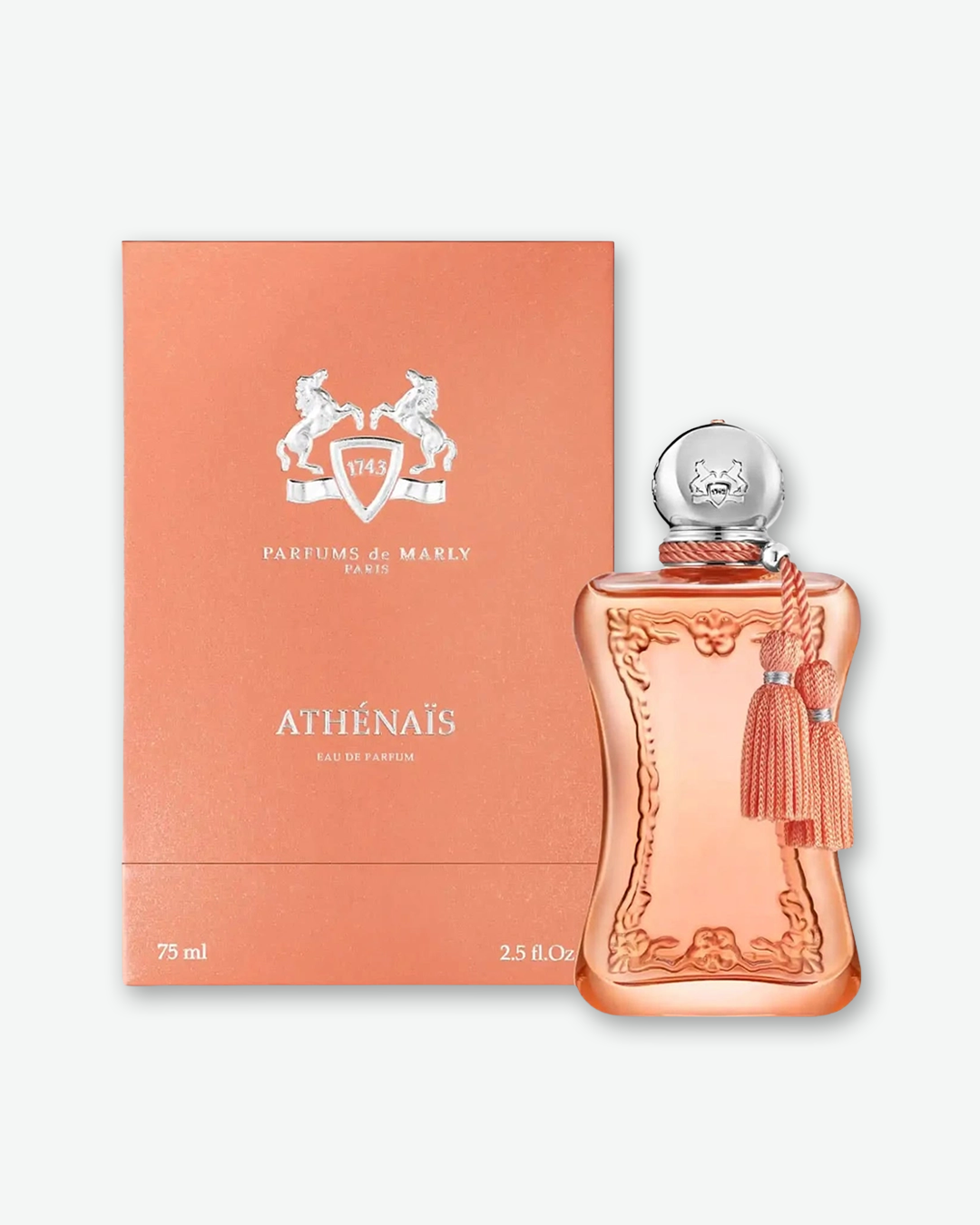 The peach-colored Parfums de Marly perfume bottle stands next to its square presentation box on a light gray background. The box matches the soft peach hue of the fragrance and features a silver-embossed crest of two rearing horses above the text 'PARFUMS de MARLY PARIS'. Lower on the box, the fragrance name 'ATHÉNAÏS' is printed in silver letters above 'EAU DE PARFUM', with '75 ml' and '2.5 fl.oz' visible at the bottom corners.