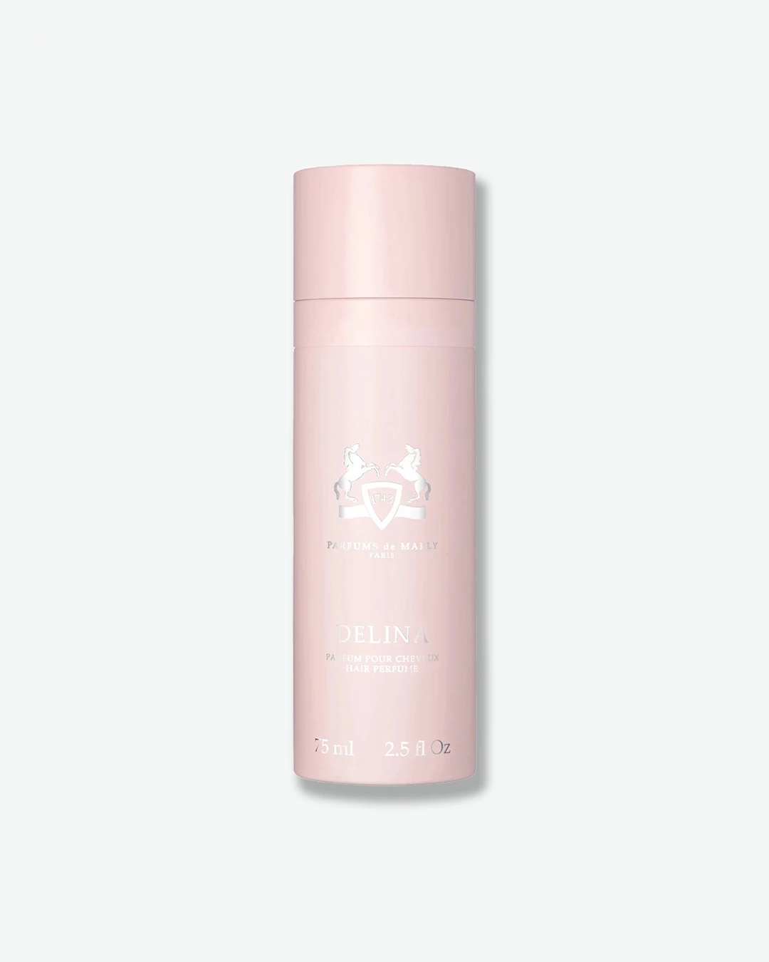 A studio product shot of Parfums de Marly Delina Hair Perfume against a light gray background. The sleek, cylindrical spray bottle features a solid, light pastel pink finish with a matching cap. The front is detailed with an embossed silver equestrian crest and the name 'DELINA PARFUM POUR CHEVEUX HAIR PERFUME' in metallic silver text.