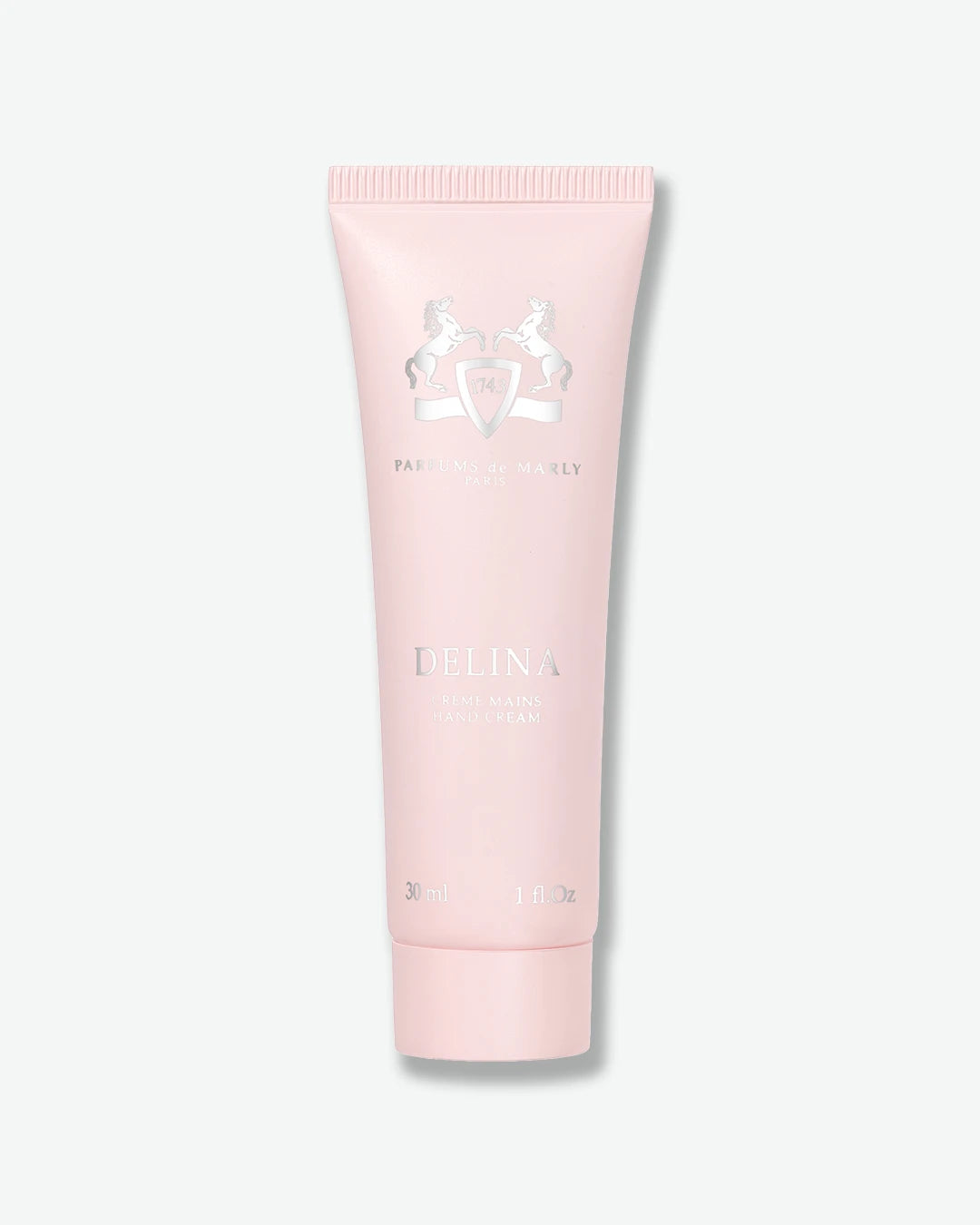 A light pink squeeze tube of Delina Hand Cream by Parfums de Marly, centered on a light gray background.