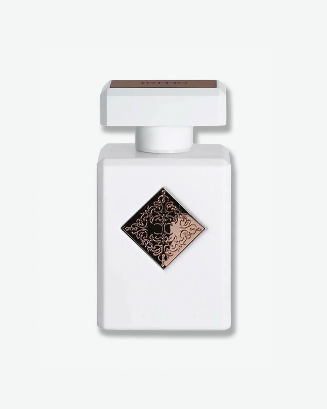Initio Parfums Privés fragrance in a clean matte white square bottle, featuring a centered rose gold or bronze diamond badge with an intricate engraved filigree emblem, isolated on a light grey background.