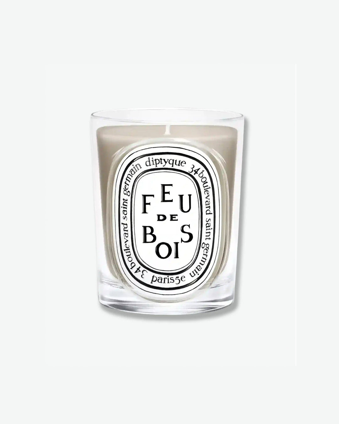 Diptyque Feu de Bois scented candle showing light beige wax in a classic clear glass jar with the signature white oval logo, isolated on a light grey background.
