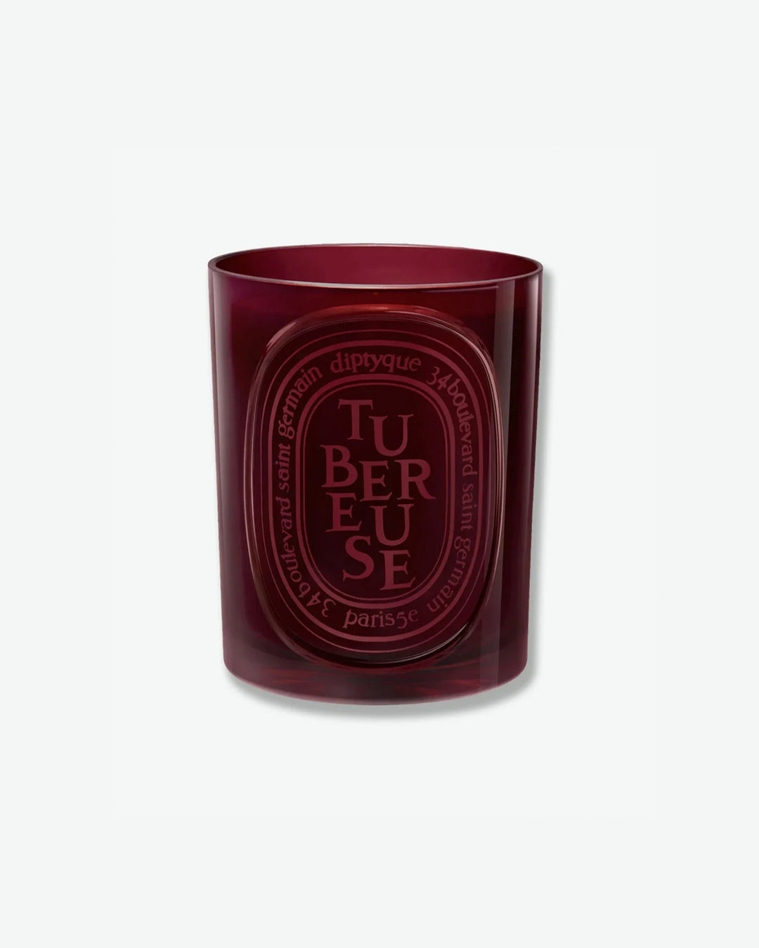 Diptyque Tubéreuse scented candle in a translucent burgundy red glass jar featuring a matching embossed red oval logo, isolated on a light grey background.