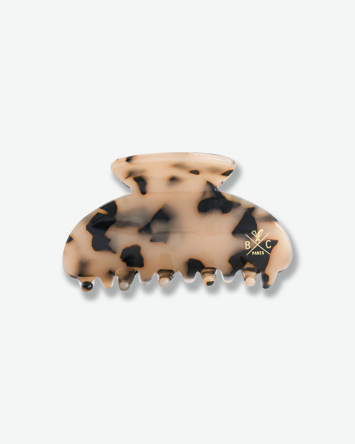 Bachca Paris hair claw clip featuring a glossy beige and black tortoiseshell pattern, curved silhouette, interlocking teeth, and gold logo detailing.