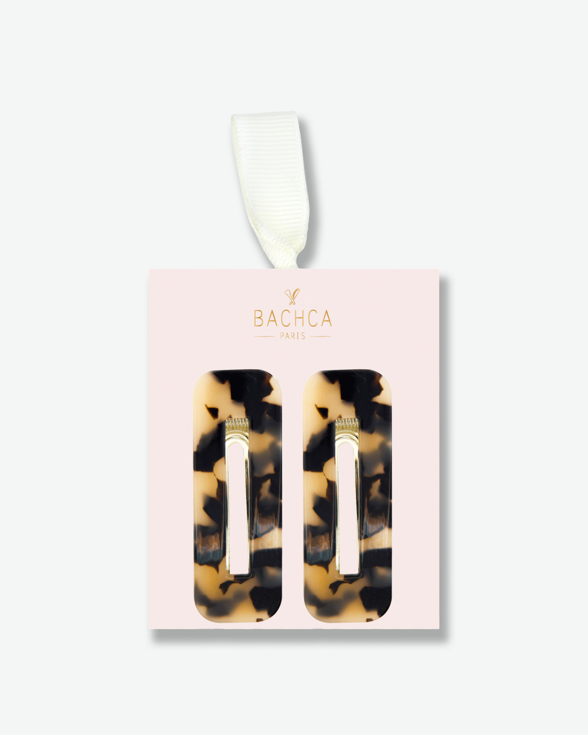 Two rectangular tortoiseshell hair clips displayed on a pale pink Bachca Paris presentation card with gold lettering and an ivory ribbon.